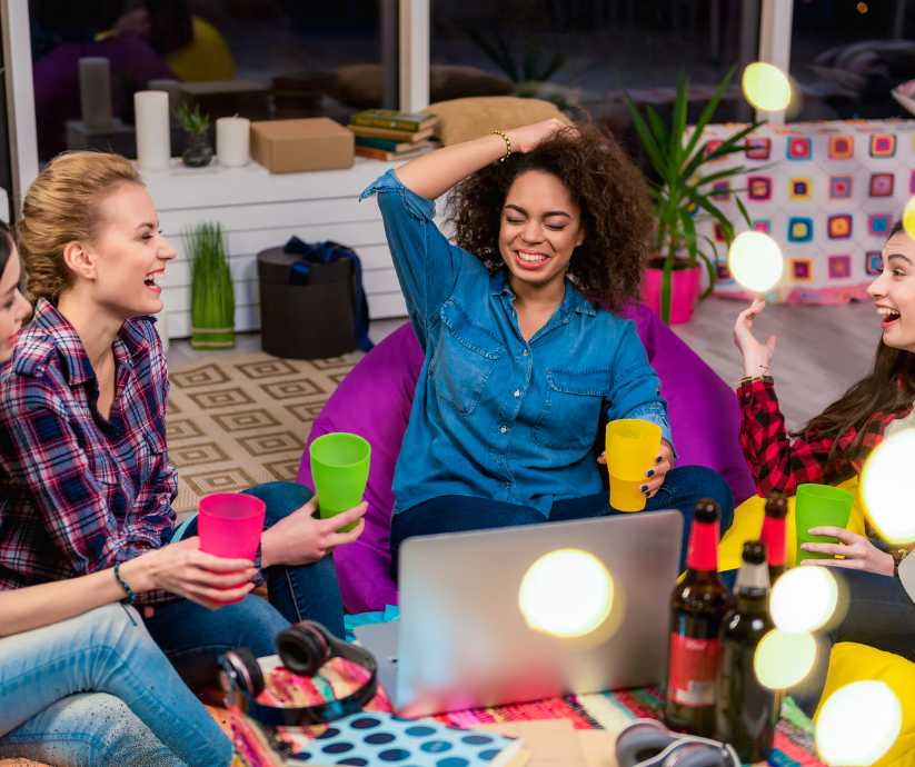 4 women sitting on the floor laughing and drinking