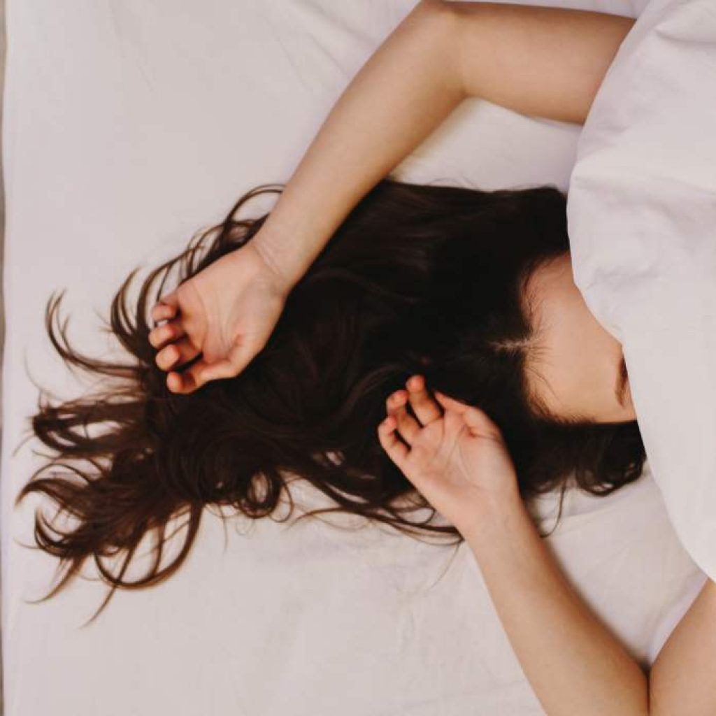 girl laying in bed with sheet over her face