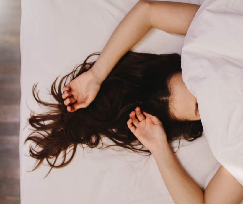 girl laying in bed with sheet over her face