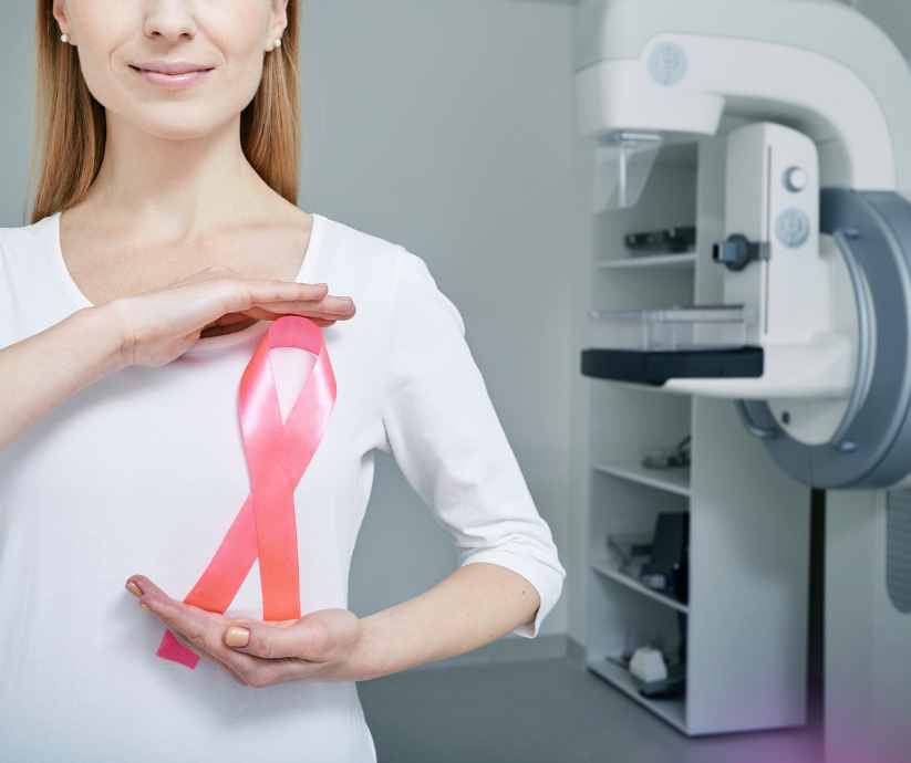 Woman holding large pink breast cancer ribbon in exam room