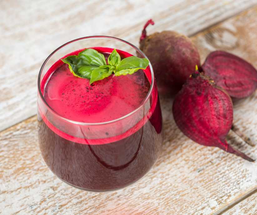 Beetroot juice and beets on a wood table