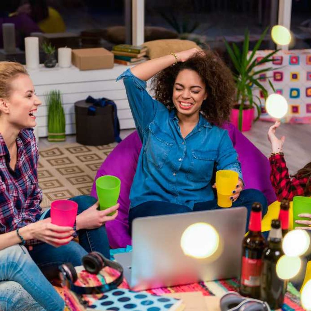 4 women sitting on the floor laughing and drinking