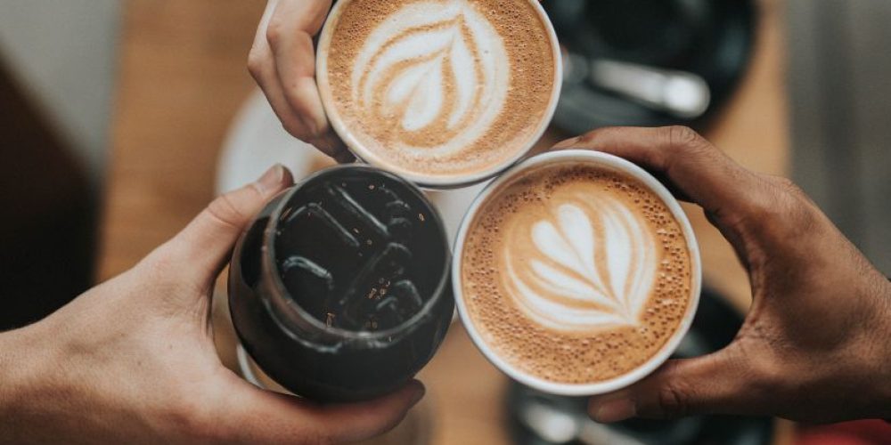 3 people clinking their coffees together